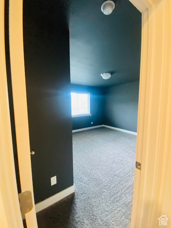 Empty room featuring dark carpet and baseboards