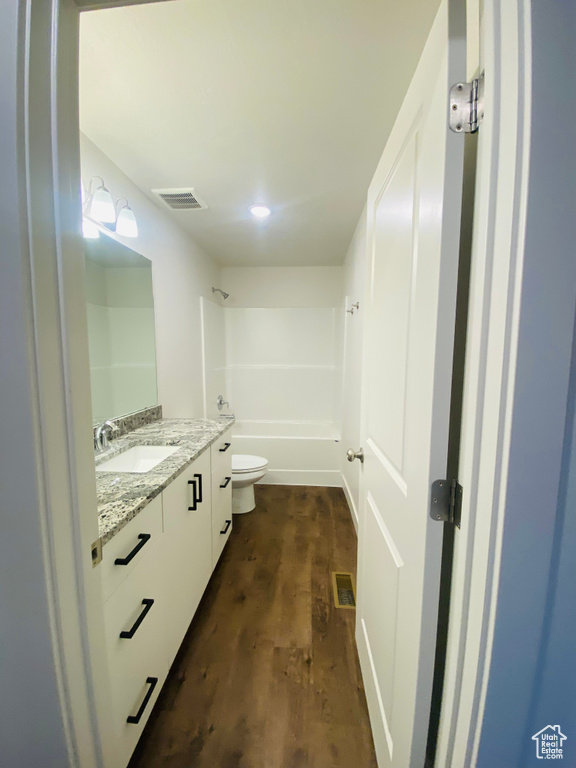 Bathroom featuring vanity, wood finished floors, toilet, and shower / washtub combination