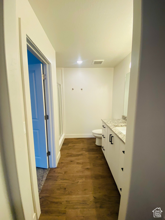 Full bathroom featuring vanity, toilet, wood finished floors, a shower stall, and baseboards