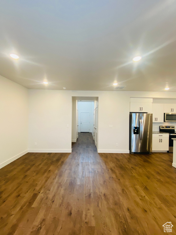 Unfurnished living room with baseboards, recessed lighting, and dark wood-type flooring