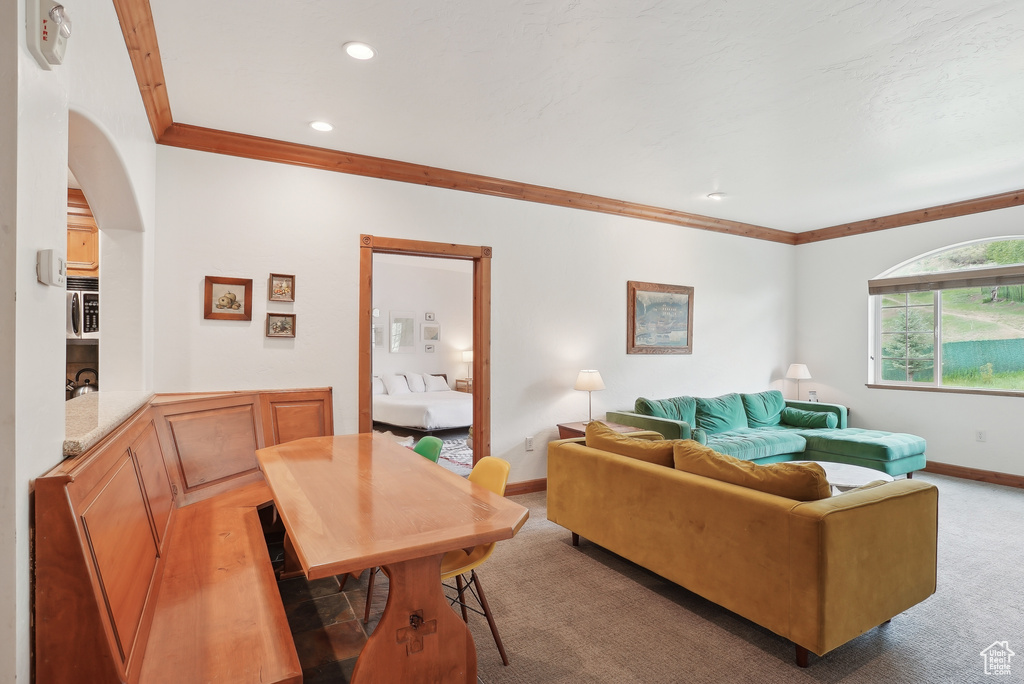 Living room with crown molding, baseboards, light carpet, arched walkways, and recessed lighting