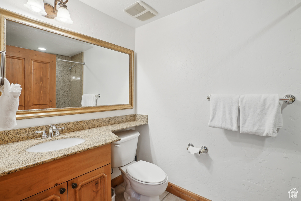 Full bath with vanity, toilet, a shower, and baseboards