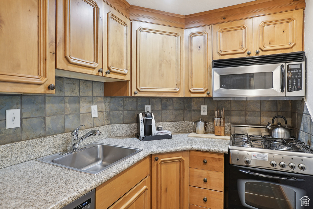 Kitchen featuring stainless steel appliances, a sink, light countertops, and backsplash