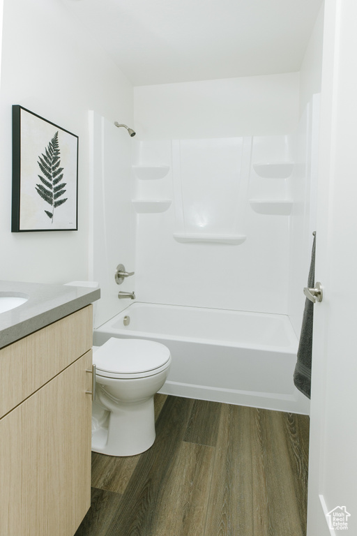 Bathroom with wood finished floors, toilet, vanity, and shower / bathtub combination