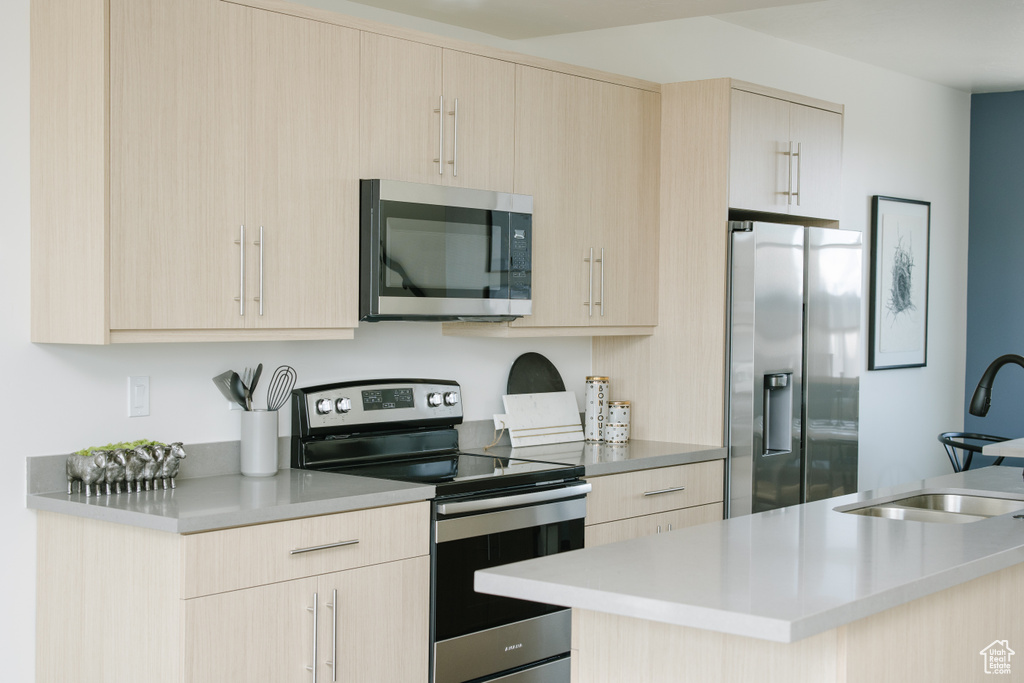 Kitchen featuring appliances with stainless steel finishes, a sink, light brown cabinets, and light countertops