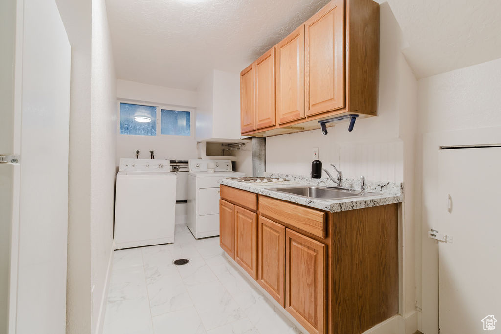 Laundry area with washing machine and dryer, light marble finish floors, and cabinet space