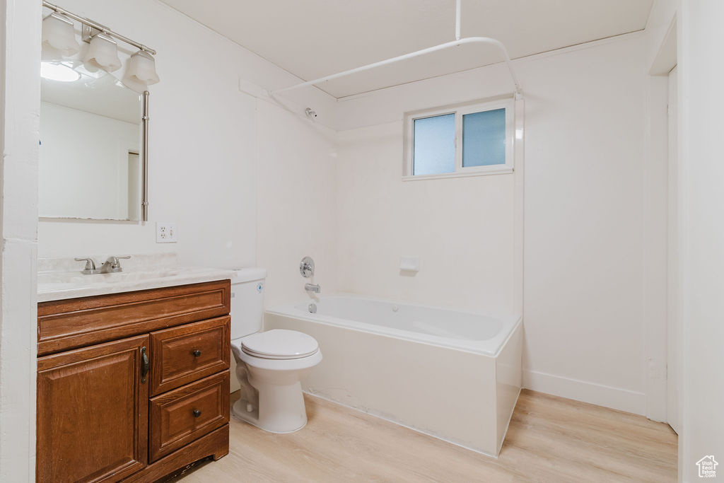 Bathroom with wood finished floors, toilet, vanity, and shower / bath combination