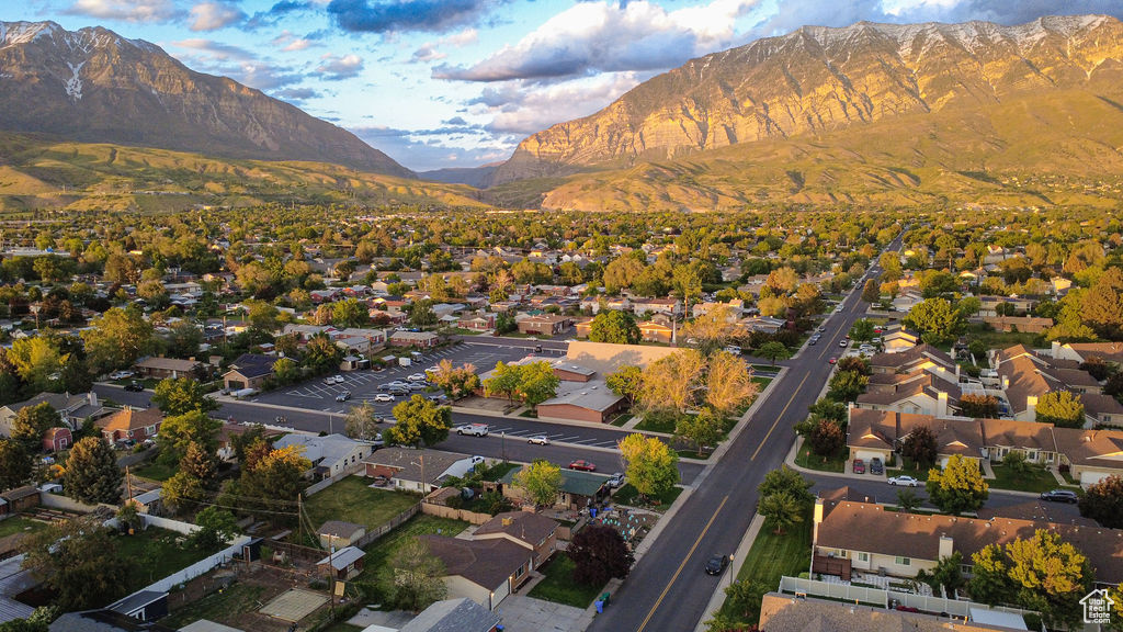 Aerial view of property and surrounding area featuring mountains and nearby suburban area