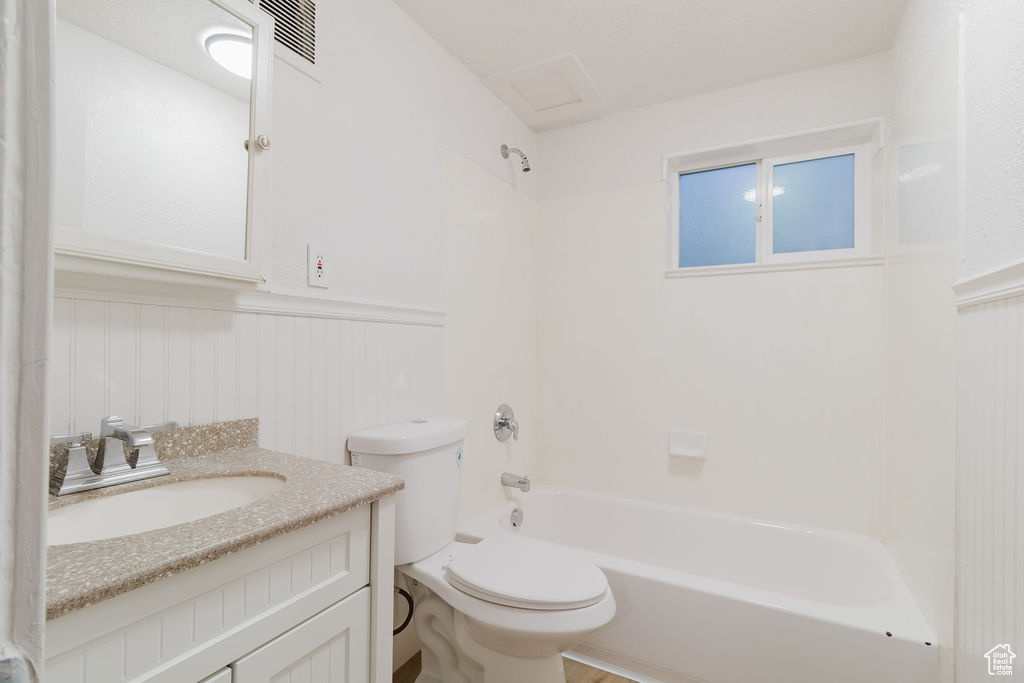Full bath with a wainscoted wall, toilet, vanity, and tub / shower combination