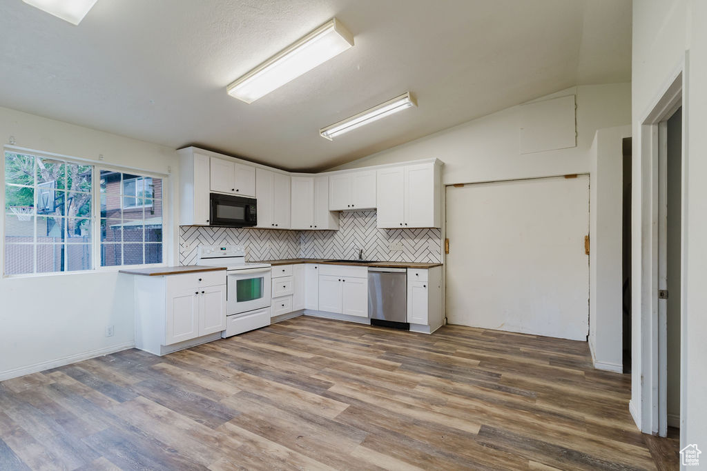 Kitchen with electric range, black microwave, stainless steel dishwasher, vaulted ceiling, and backsplash