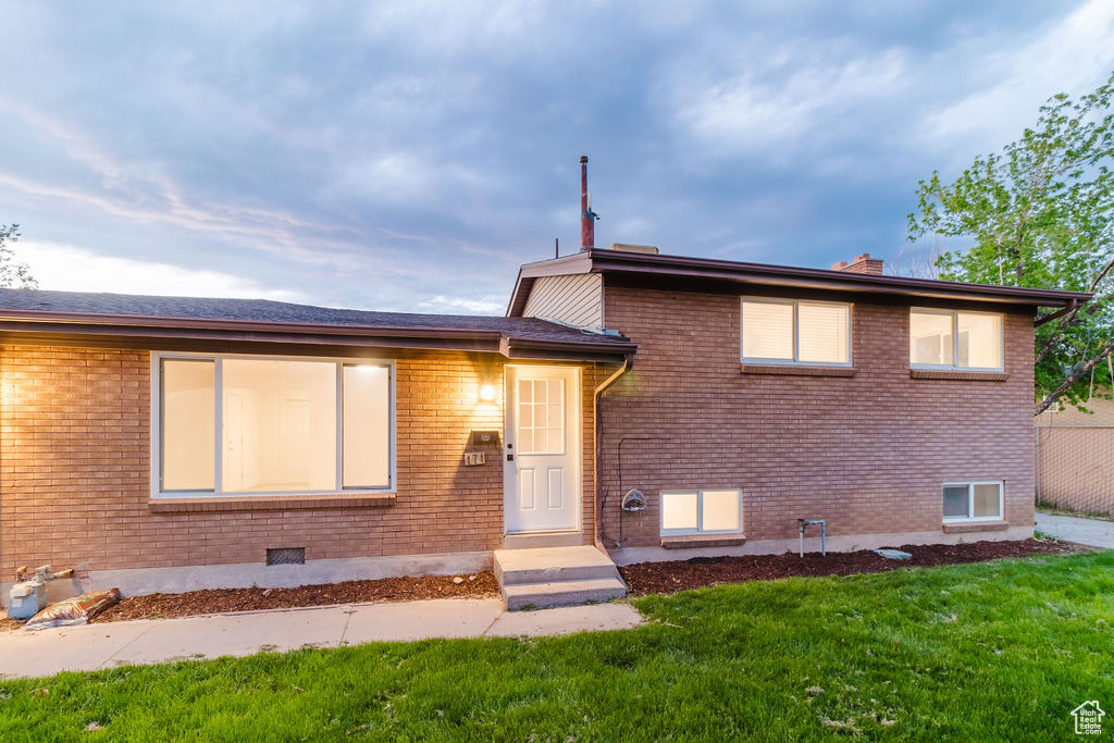 Tri-level home featuring brick siding, a front lawn, and a chimney