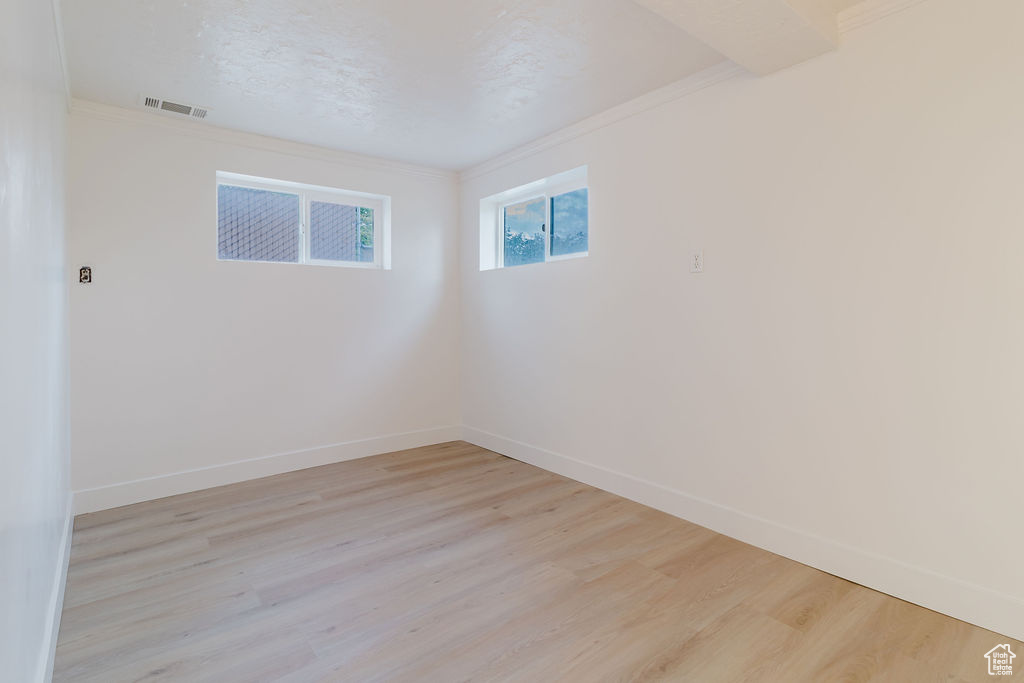 Unfurnished room with light wood-type flooring, crown molding, and baseboards