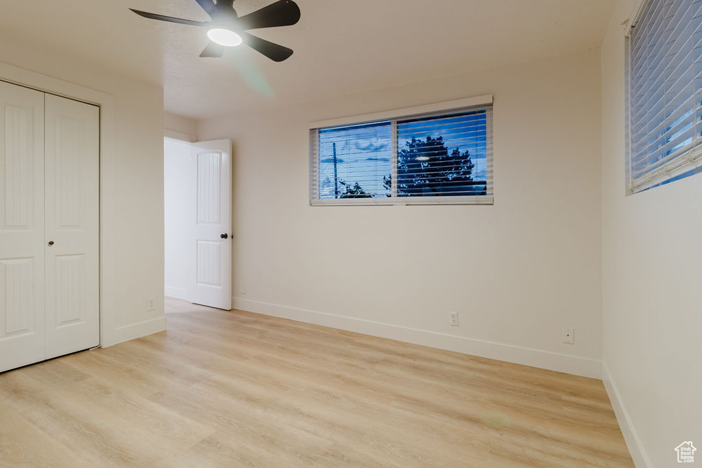 Unfurnished bedroom with light wood finished floors, baseboards, and a closet