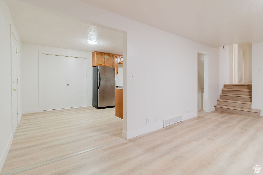 Unfurnished room with light wood-style flooring, stairway, and baseboards