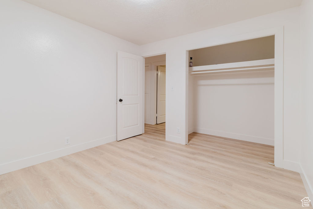 Unfurnished bedroom with wood finished floors, baseboards, and a closet