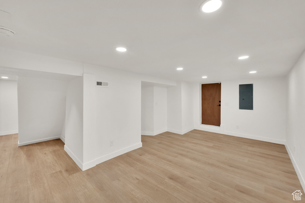 Empty room with electric panel, recessed lighting, light wood-style floors, and baseboards