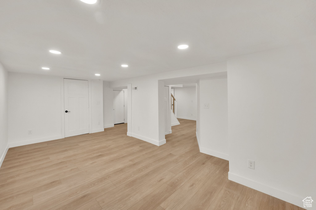 Finished basement with recessed lighting, baseboards, light wood-style floors, and stairway