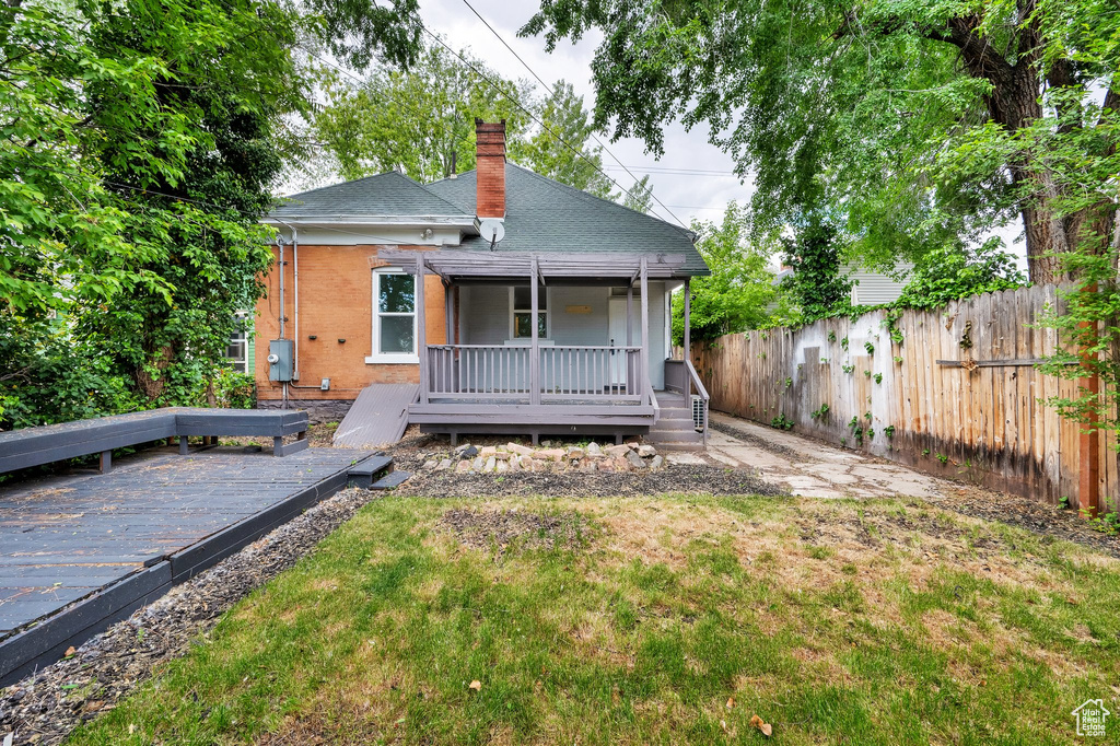 Back of property with a deck, a chimney, roof with shingles, and brick siding