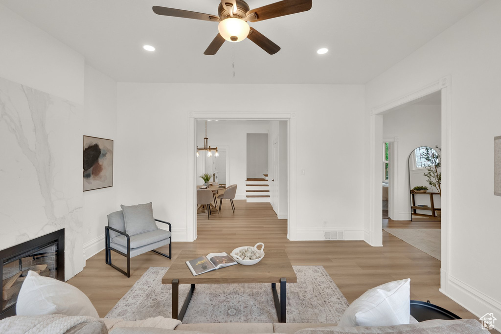 Living area featuring baseboards, light wood-style flooring, stairway, a fireplace, and recessed lighting