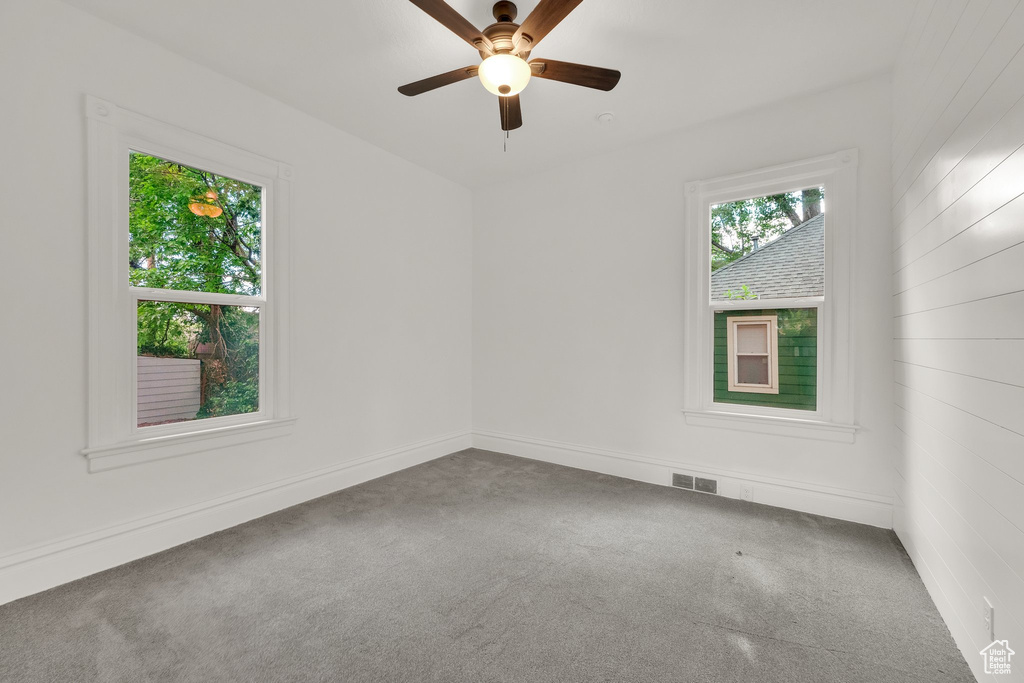Empty room with carpet flooring, a ceiling fan, and baseboards
