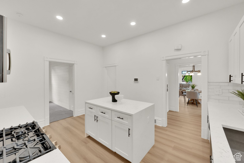 Kitchen featuring light wood-style floors, white cabinetry, recessed lighting, stovetop, and light stone counters