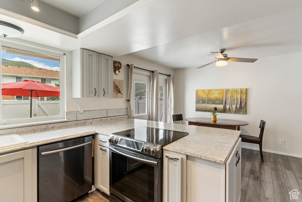 Kitchen with appliances with stainless steel finishes, a peninsula, wood finished floors, and a ceiling fan