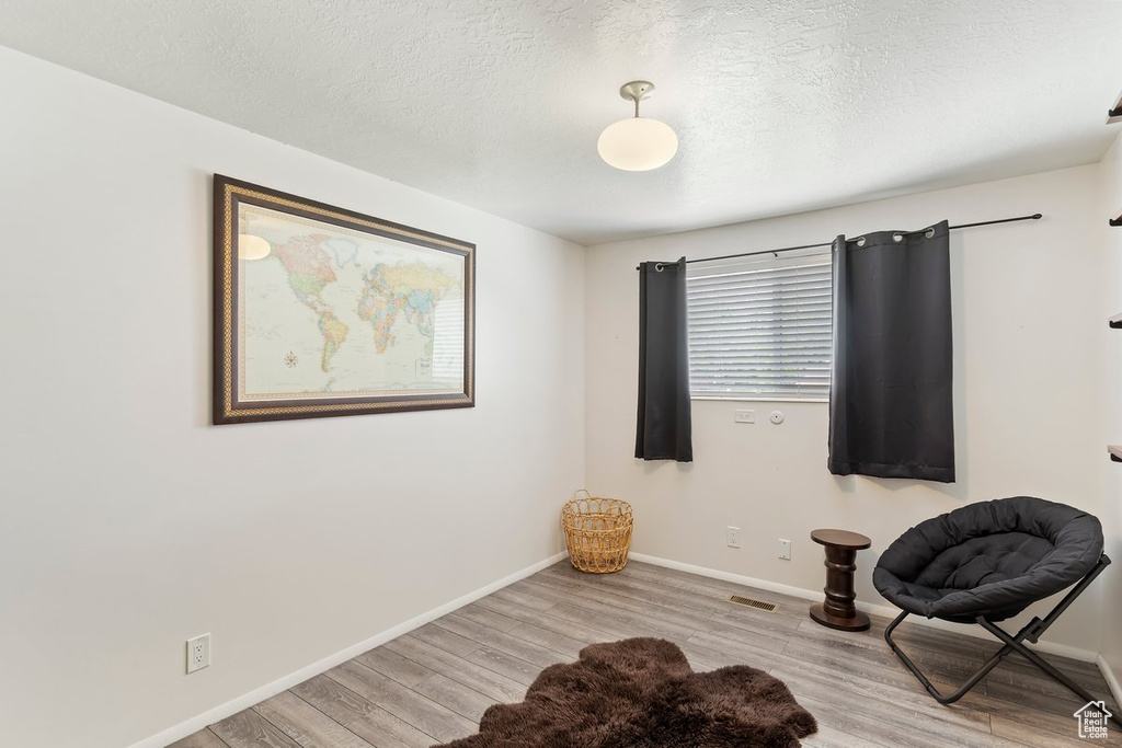 Living area with wood finished floors, baseboards, and a textured ceiling