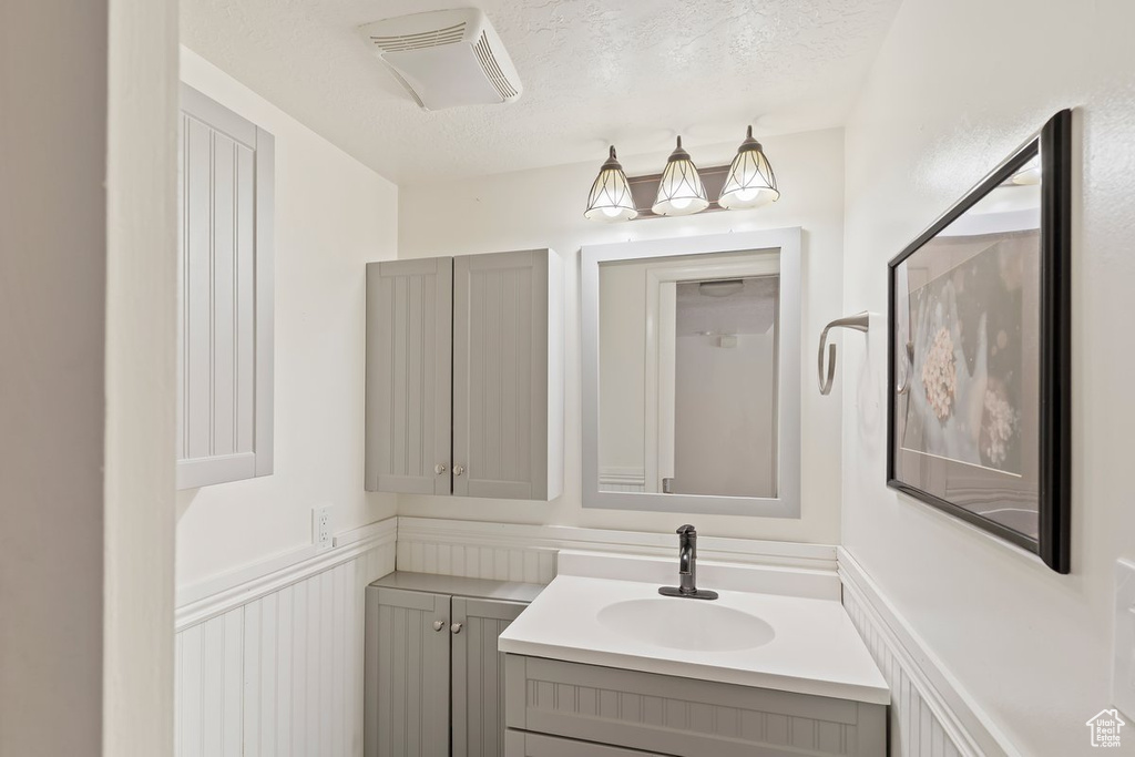 Bathroom featuring vanity, a textured ceiling, and wainscoting