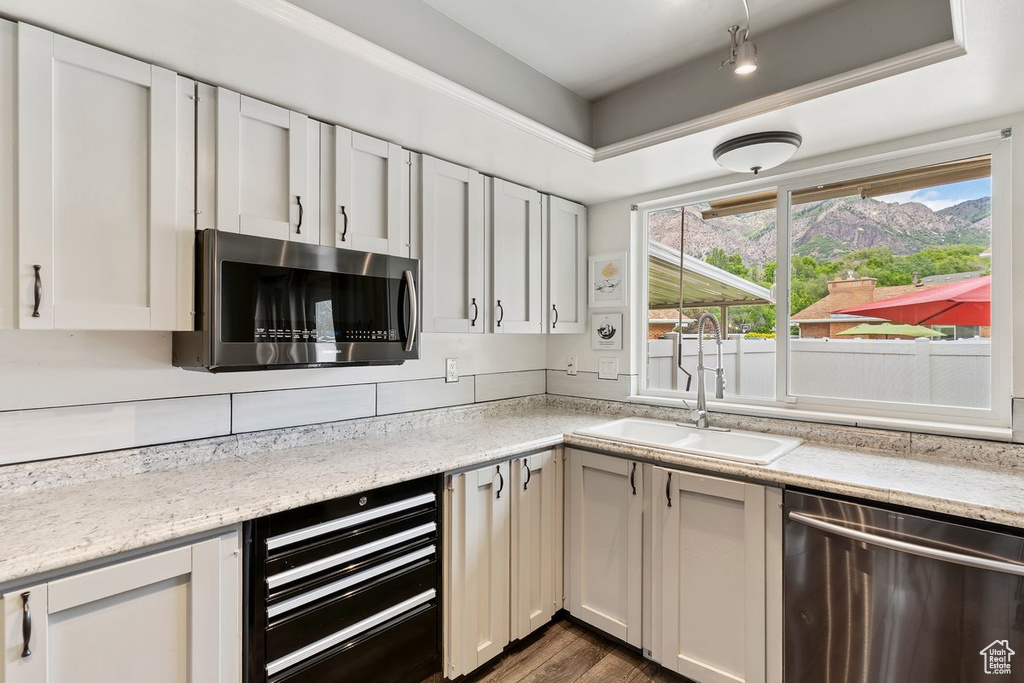 Kitchen with stainless steel appliances, a sink, wine cooler, dark wood-type flooring, and white cabinets