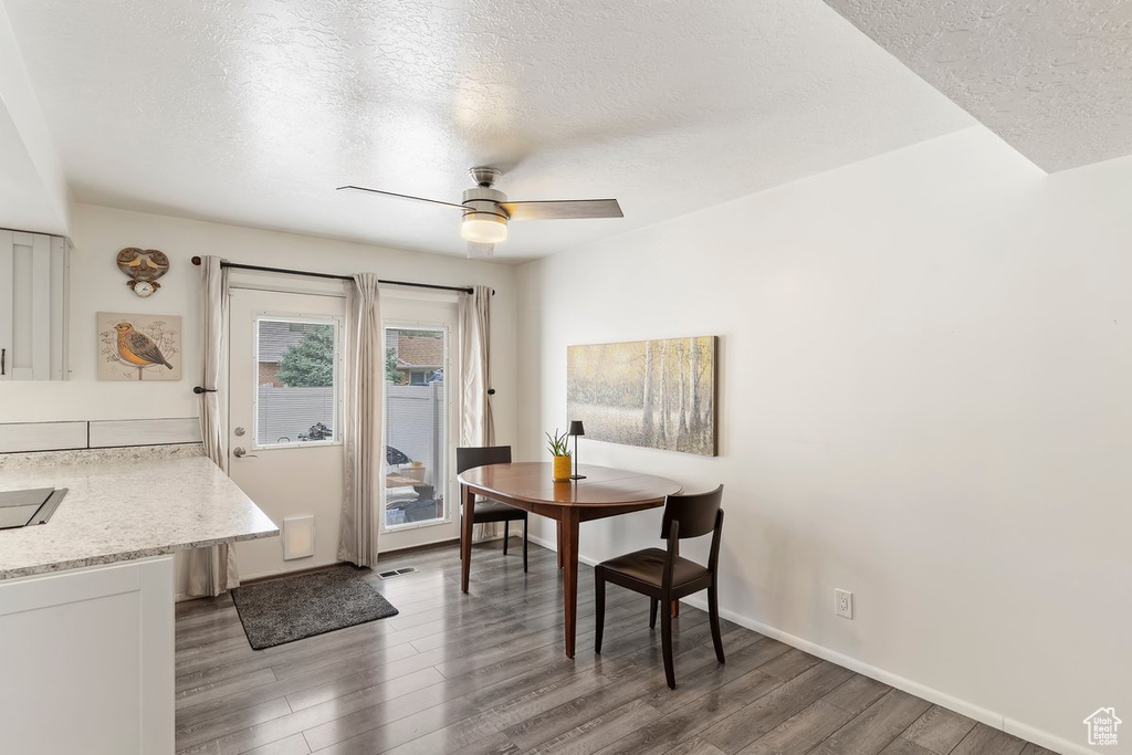 Dining room featuring a textured ceiling, wood finished floors, a ceiling fan, and baseboards
