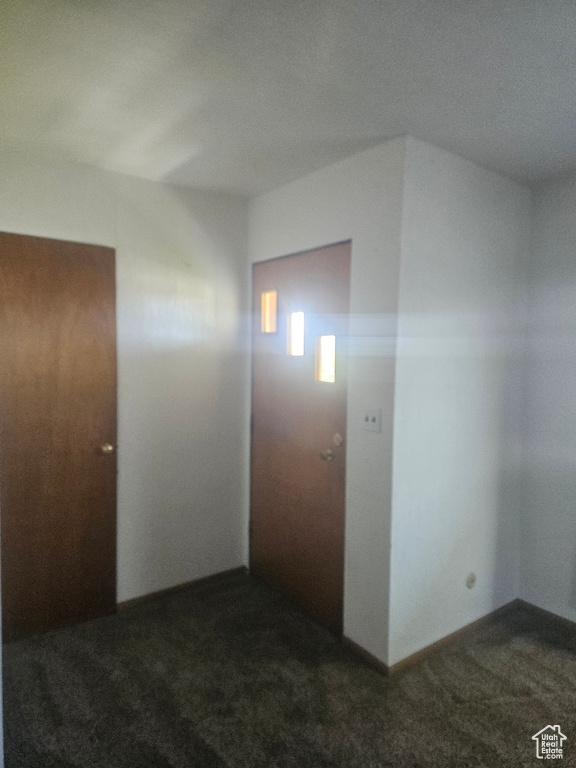 Corridor featuring dark carpet