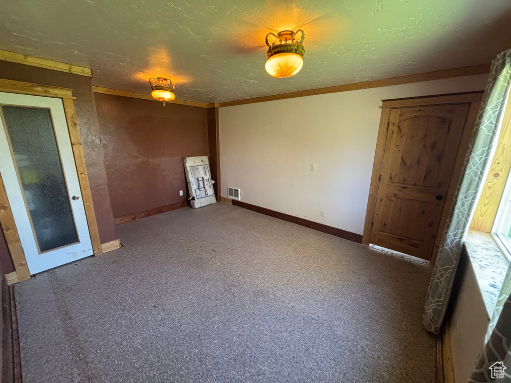 Carpeted empty room with baseboards, a textured ceiling, and ornamental molding