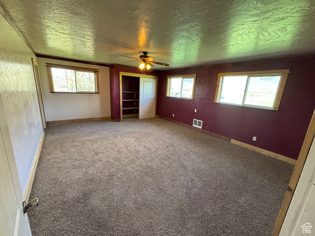Unfurnished bedroom with a textured ceiling, carpet, baseboards, and a ceiling fan