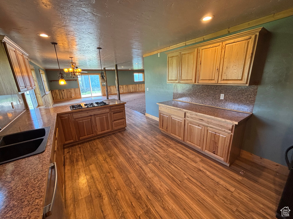 Kitchen with dark wood-style flooring, gas cooktop, a chandelier, a peninsula, and pendant lighting