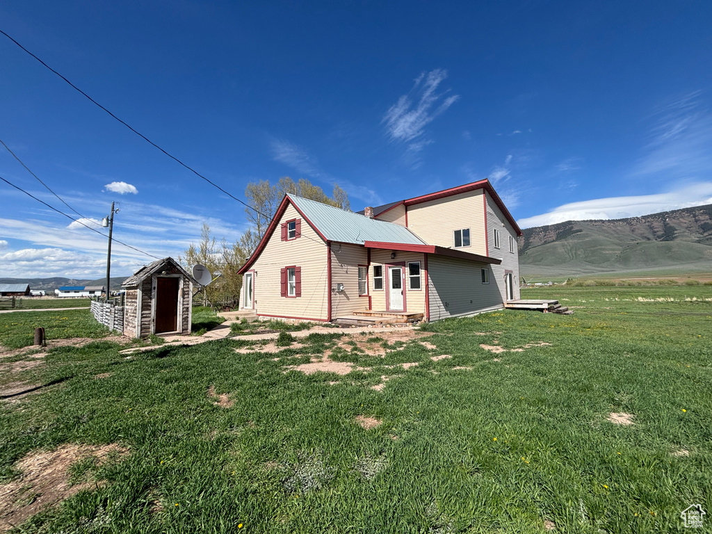 View of side of home featuring a yard, metal roof, entry steps, and a mountain view
