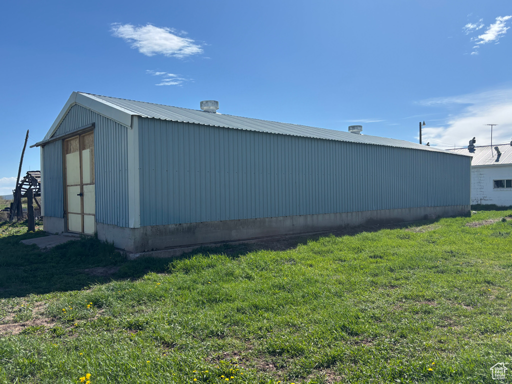 View of property exterior with a lawn, a pole building, an outdoor structure, and metal roof