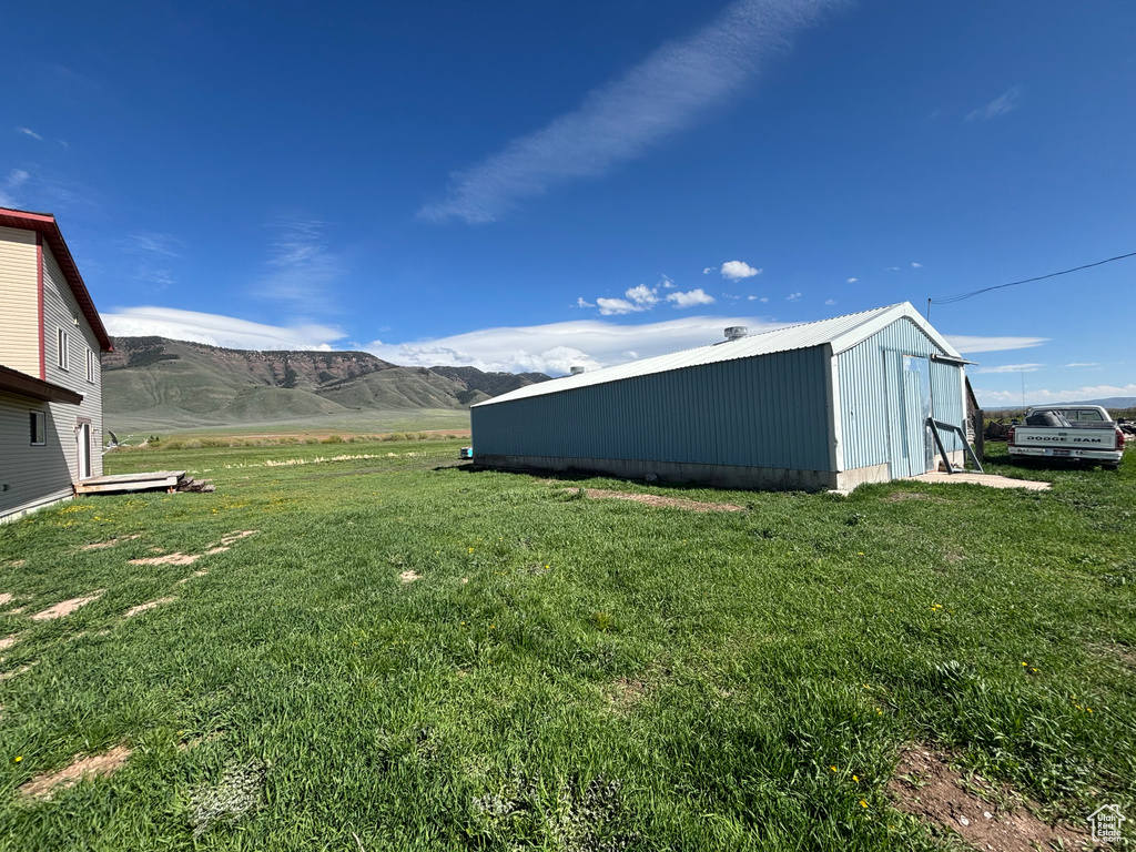 View of grassy yard featuring an outbuilding, a mountain view, and a pole building