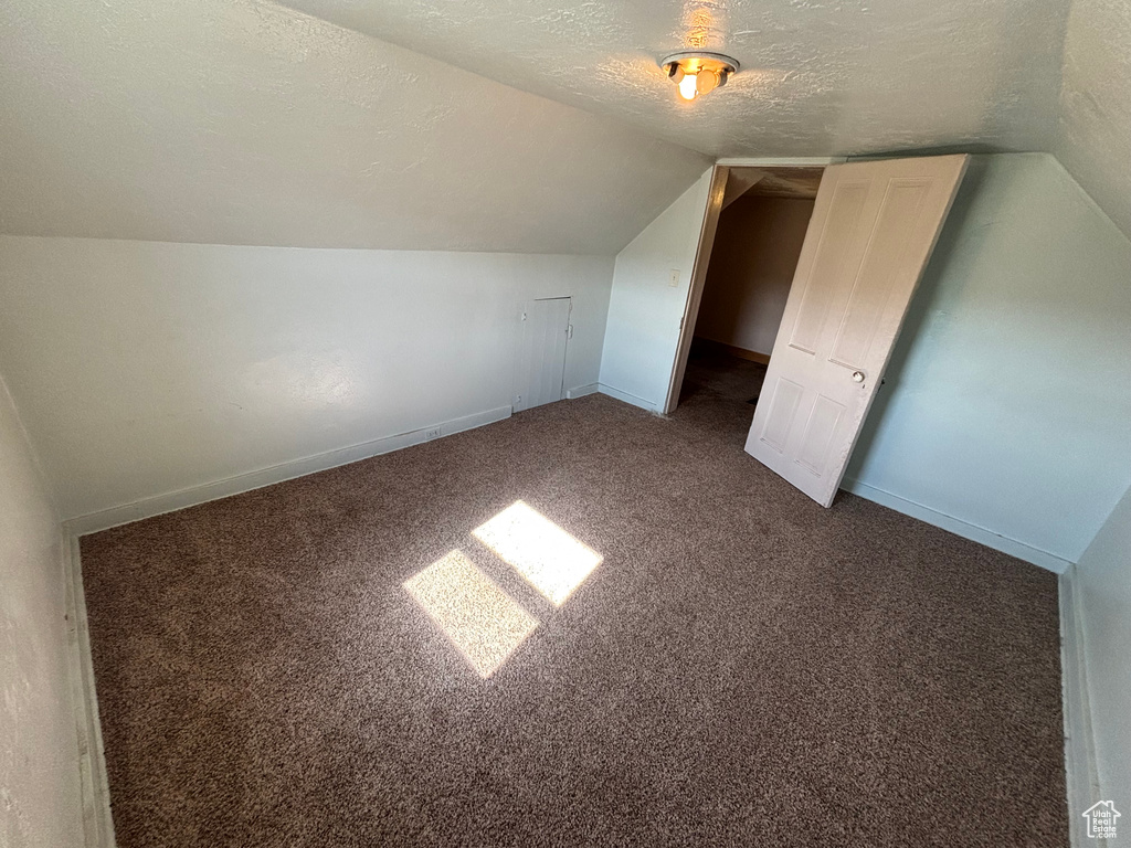 Bonus room featuring lofted ceiling, carpet flooring, a textured ceiling, and baseboards
