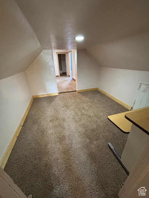 Bonus room with vaulted ceiling, carpet flooring, and baseboards