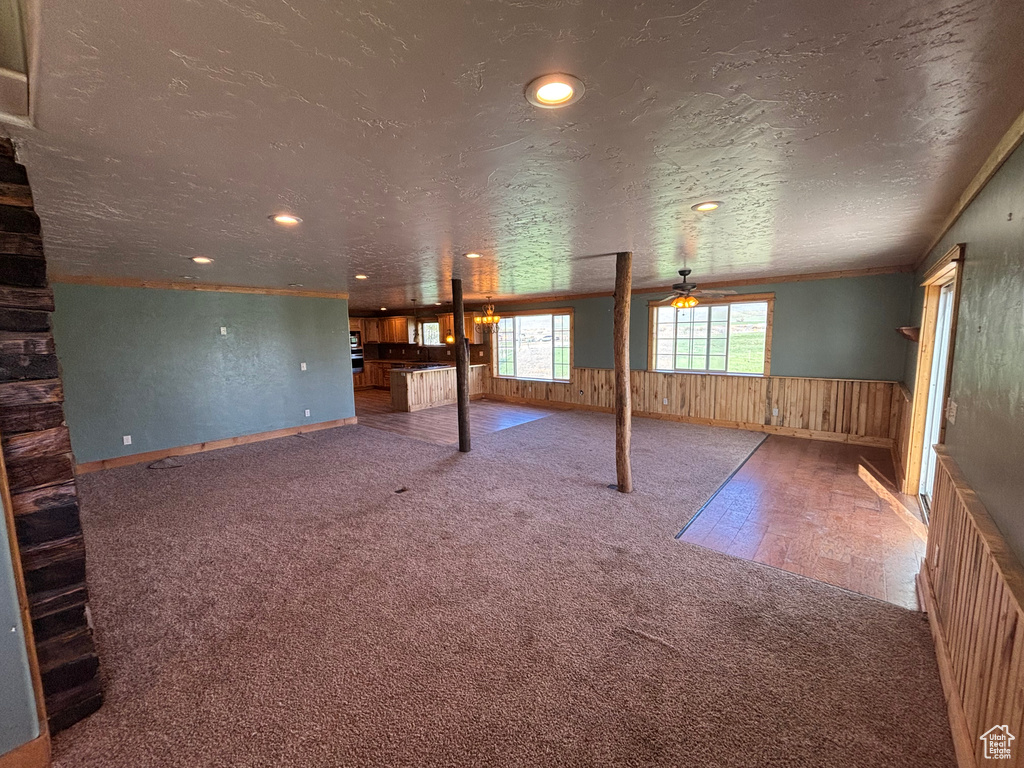 Unfurnished living room with carpet floors, ceiling fan, a wainscoted wall, recessed lighting, and wood walls