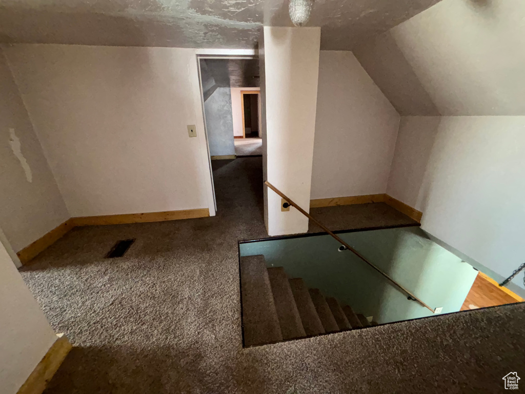 Staircase featuring carpet flooring, lofted ceiling, and baseboards