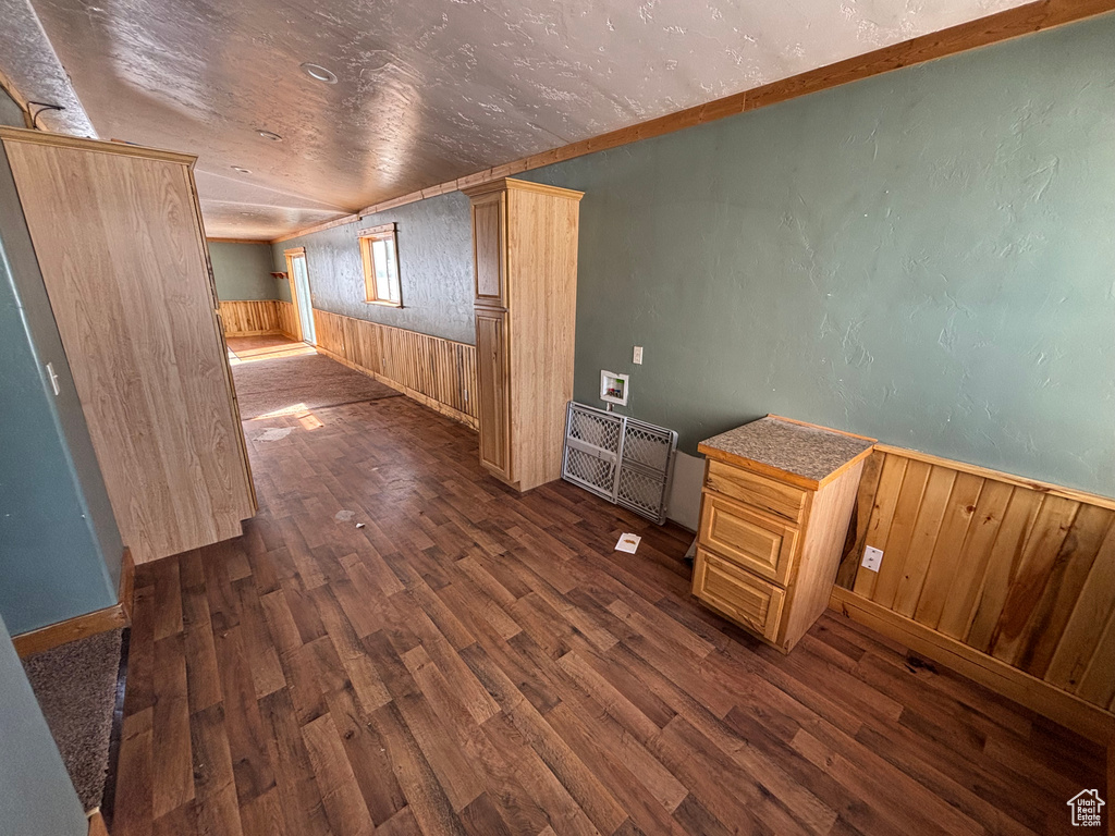 Empty room with dark wood-type flooring, wood walls, and a wainscoted wall