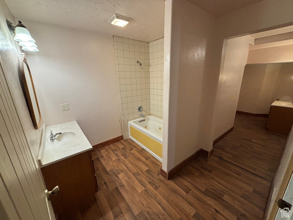 Bathroom with vanity, wood finished floors, baseboards, and tub / shower combination