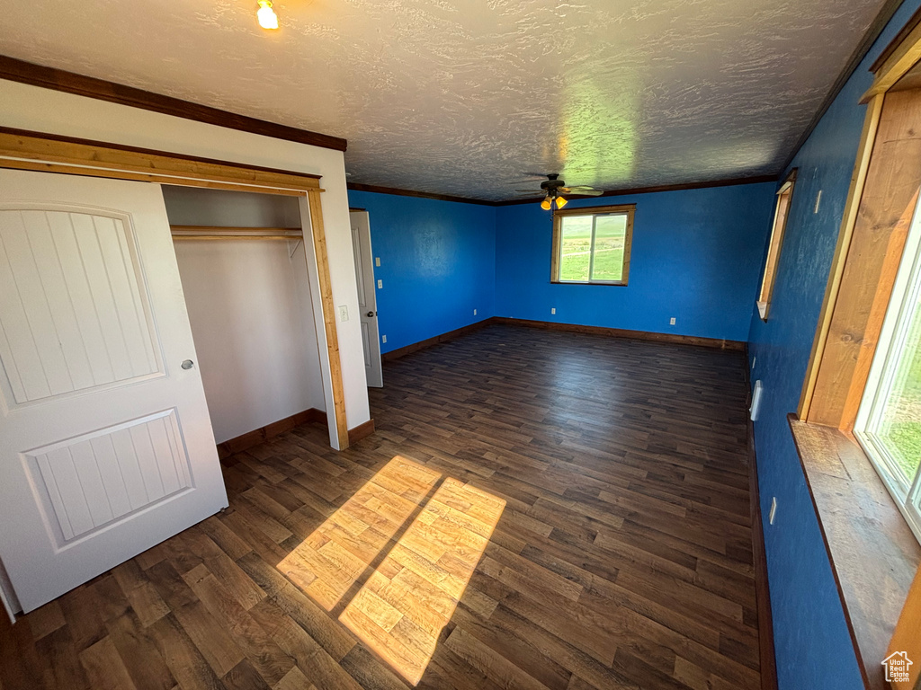 Unfurnished bedroom featuring dark wood-style flooring, a textured ceiling, baseboards, and a closet