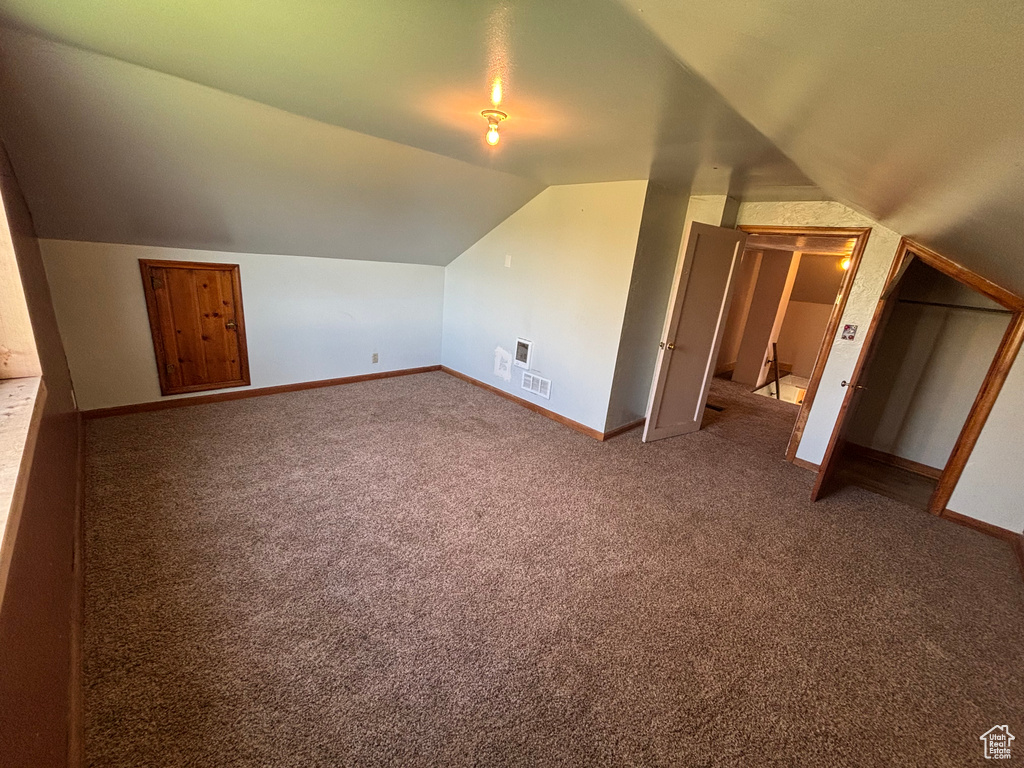 Additional living space with lofted ceiling, baseboards, and carpet floors