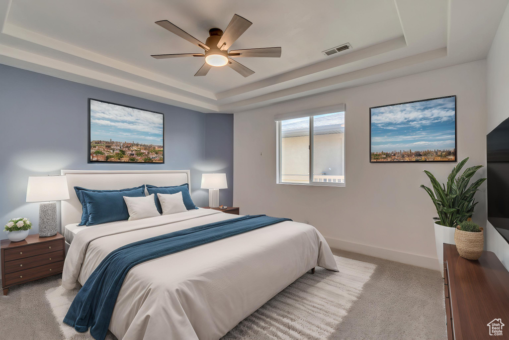 Bedroom with a raised ceiling, light colored carpet, baseboards, and a ceiling fan