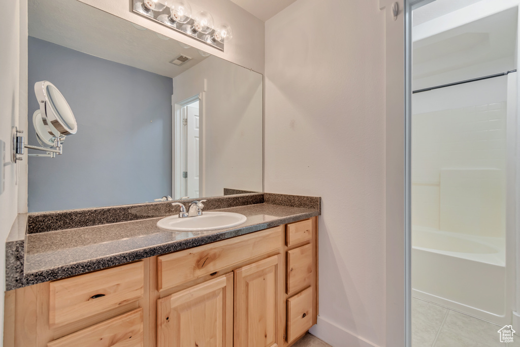 Full bath with vanity, tile patterned floors, and shower / tub combination