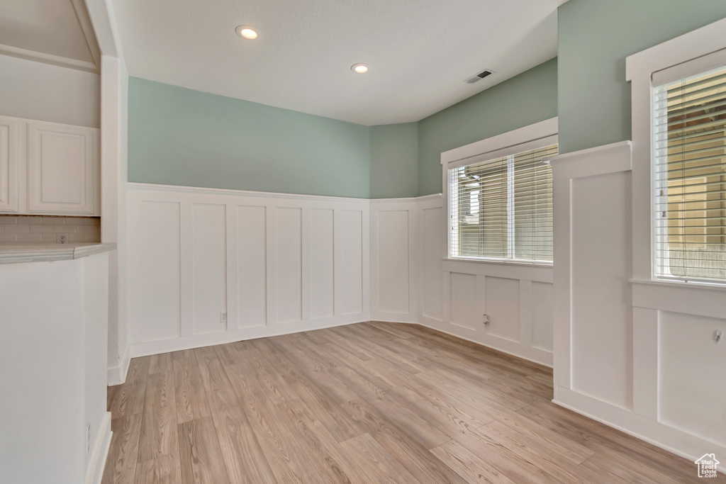 Spare room with a decorative wall, a wainscoted wall, light wood-type flooring, and recessed lighting