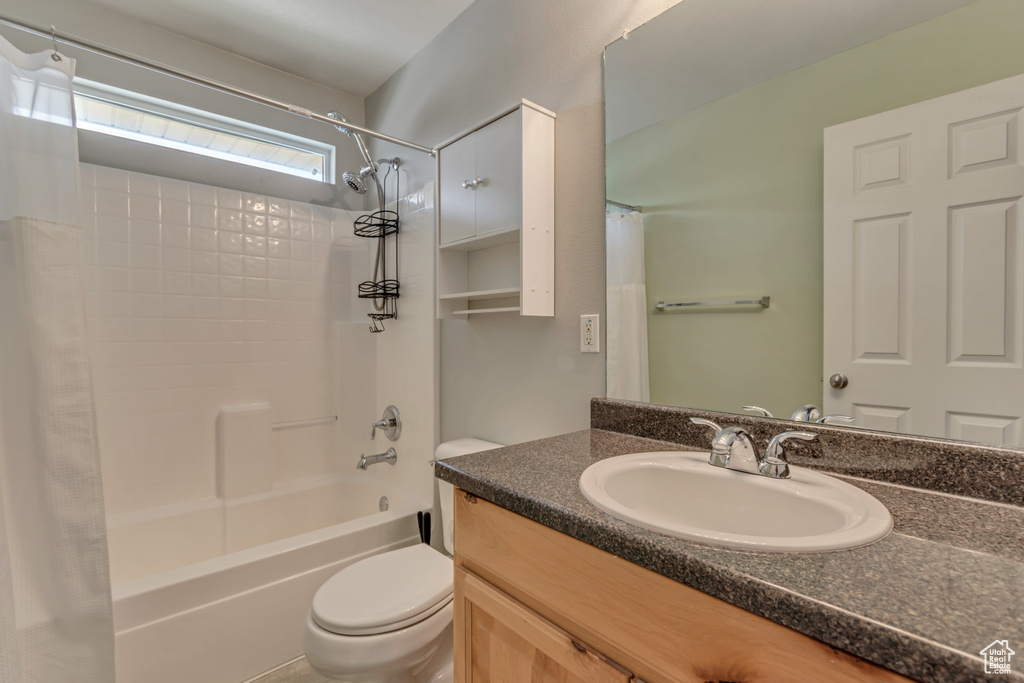 Bathroom featuring shower / bath combo with shower curtain, toilet, and vanity