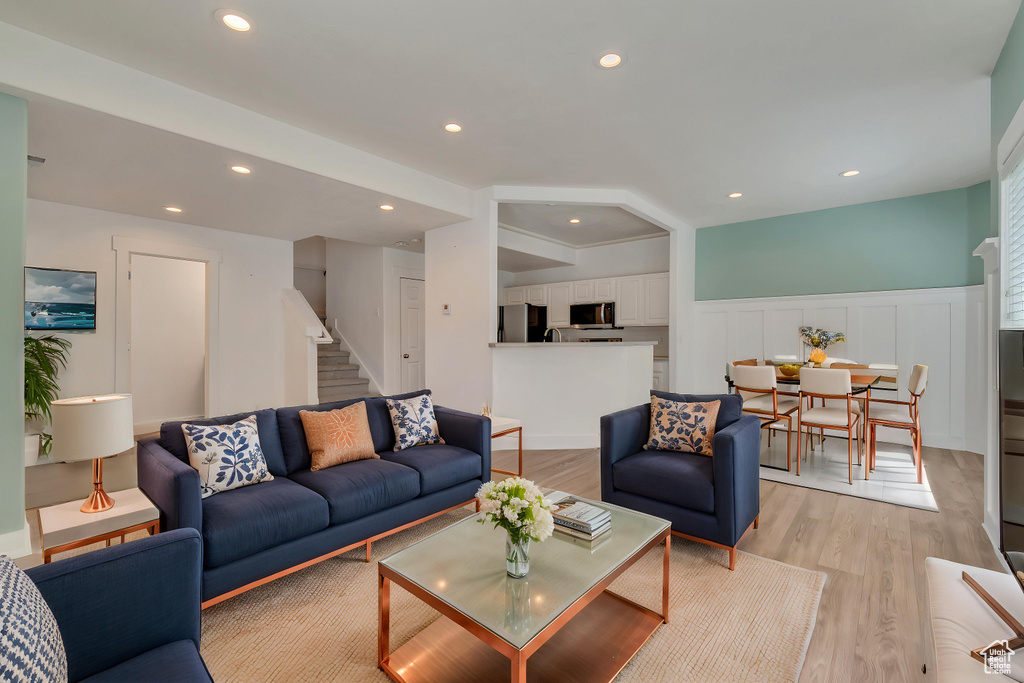 Living area with stairs, light wood-type flooring, wainscoting, recessed lighting, and a decorative wall